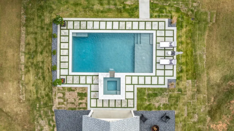 An aerial view of a large swimming pool surrounded by a lush green lawn.