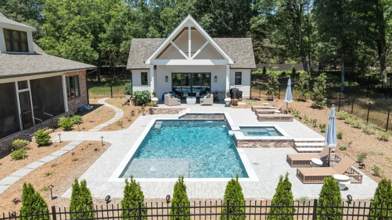 Backyard pool with lounge chairs, cabana, and landscaped patio beside a house