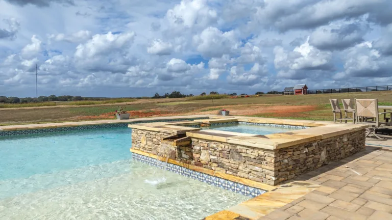 A large swimming pool with a hot tub in the middle of it.