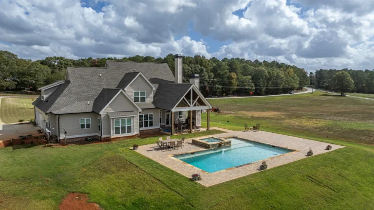 An aerial view of a house with a large swimming pool in the backyard.