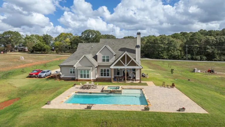 An aerial view of a house with a large swimming pool in the backyard.