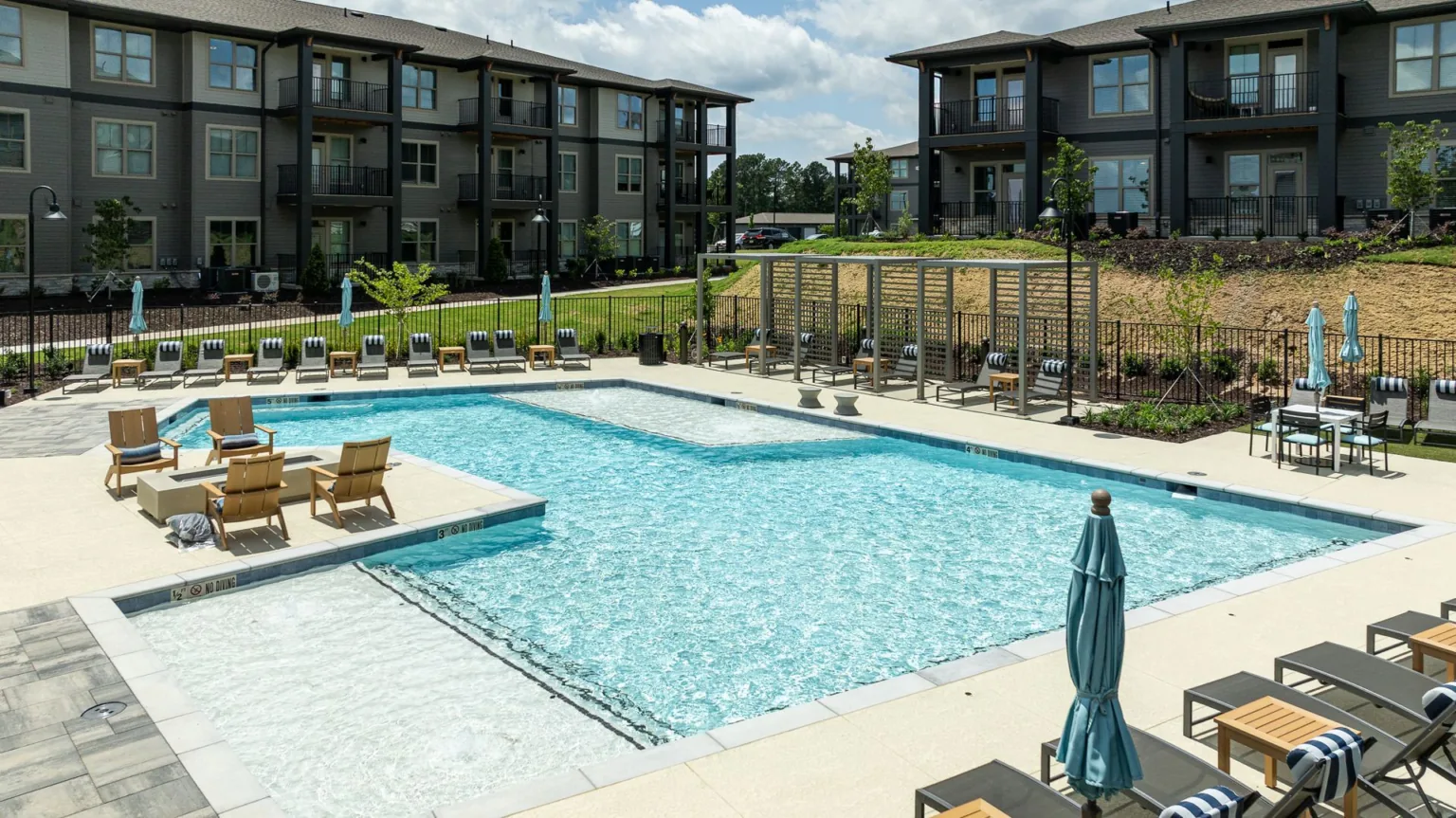 Apartment complex pool courtyard with lounge chairs and umbrellas under a cloudy sky