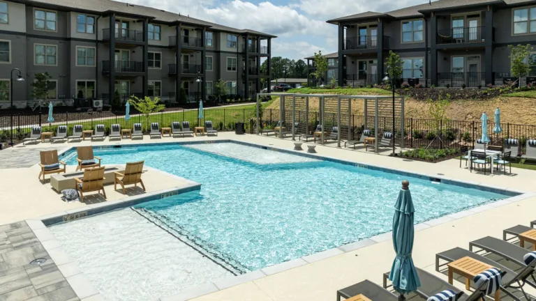 Apartment complex pool courtyard with lounge chairs and umbrellas under a cloudy sky