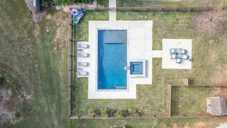 An aerial view of a large swimming pool in the backyard of a house.