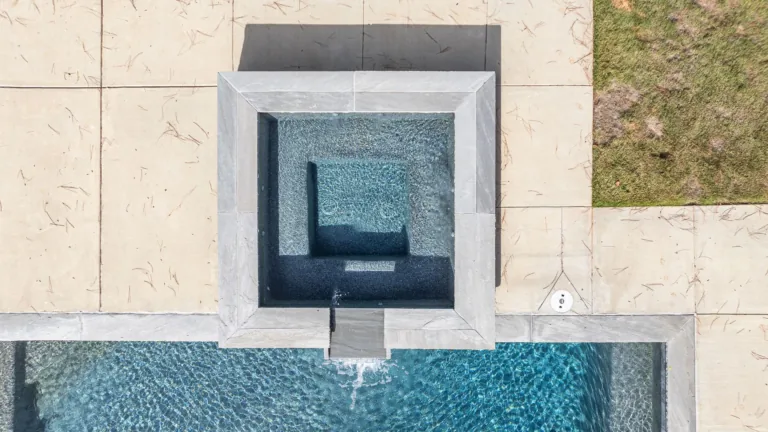An aerial view of a swimming pool with a hot tub in the middle.