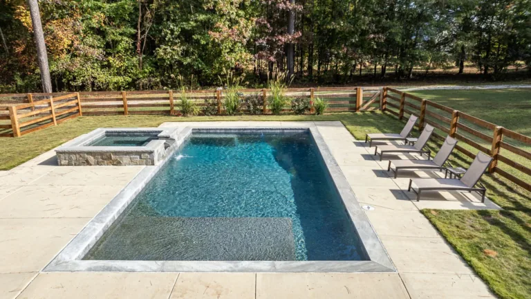 A large swimming pool surrounded by chairs and a wooden fence.