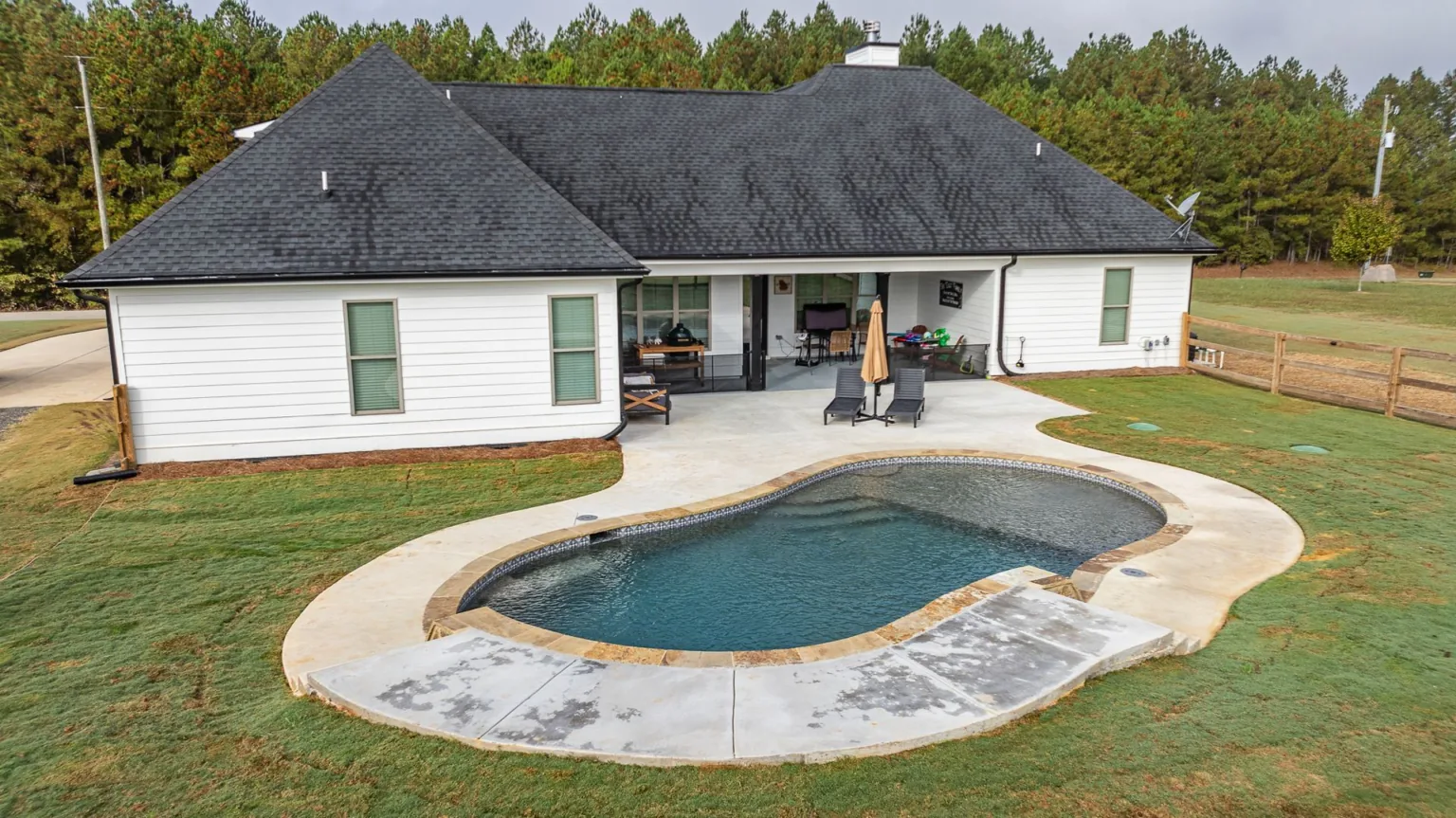 A white house with a large swimming pool in front of it.