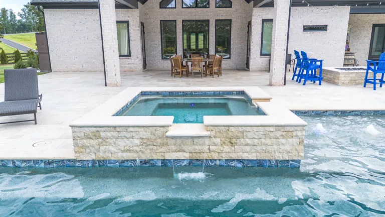 A luxury outdoor pool area with a hot tub, patio furniture, and a scenic view.