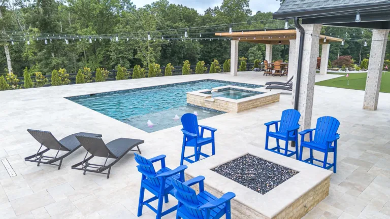 Outdoor pool and patio with blue chairs, fire pit, and lounge chairs.