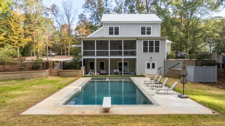A large white house with a large swimming pool in the backyard.