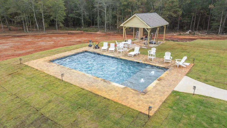 An aerial view of a large swimming pool with a gazebo in the background.