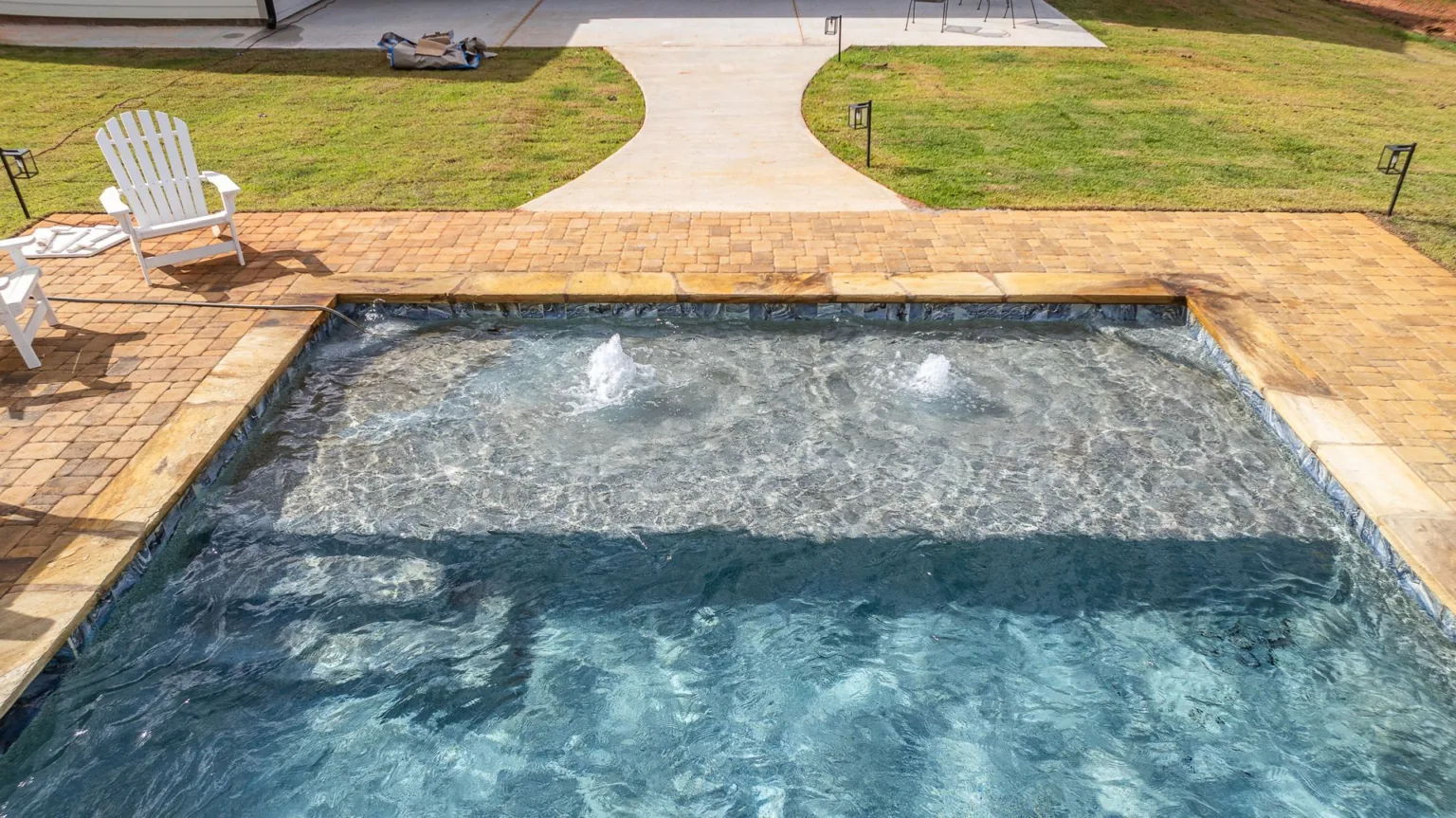There is a swimming pool with a fountain in the middle of it.