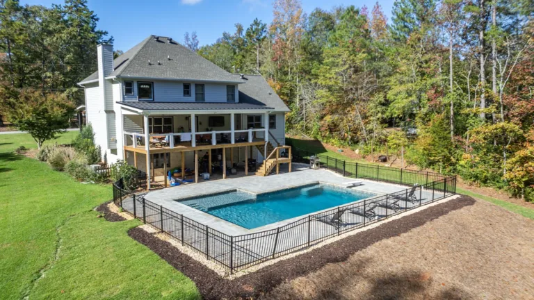 An aerial view of a large house with a large swimming pool in the backyard.
