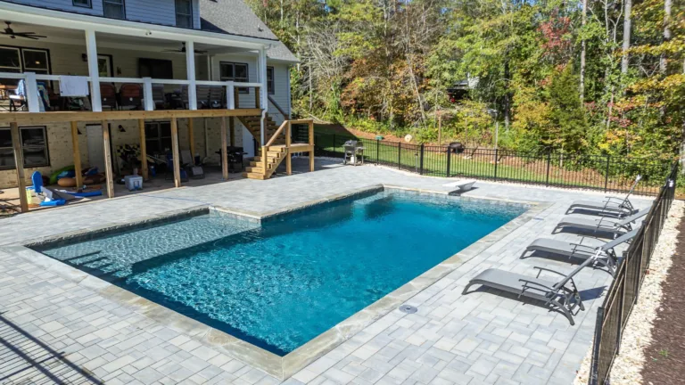 There is a large swimming pool in the backyard of a house.