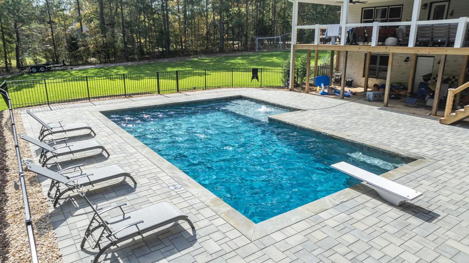 There is a large swimming pool in the backyard of a house.