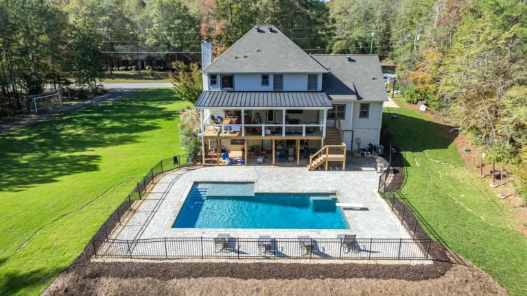 An aerial view of a house with a large swimming pool in the backyard.