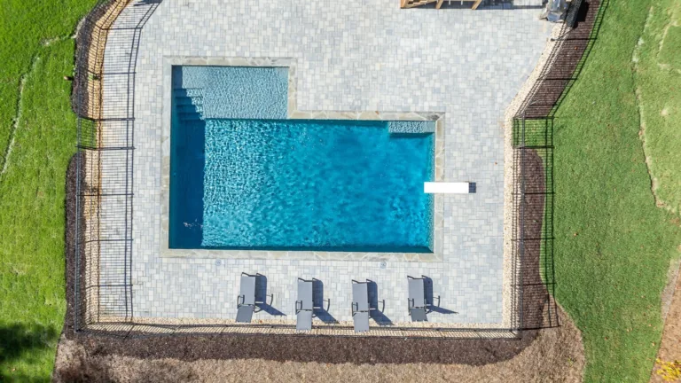 An aerial view of a large swimming pool surrounded by chairs and a fence.