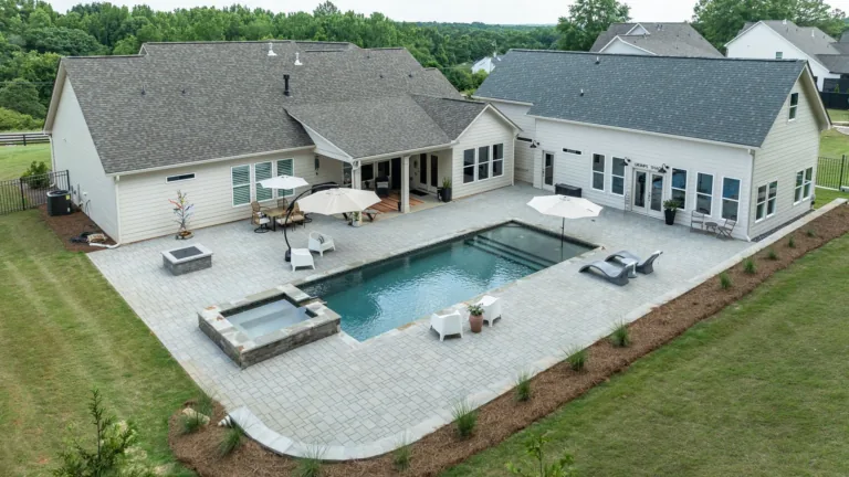 Aerial view of a modern home with a patio, swimming pool, and backyard lounge area