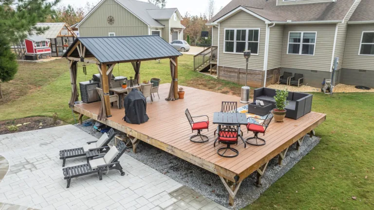 A wooden deck with a table and chairs on it in front of a house.