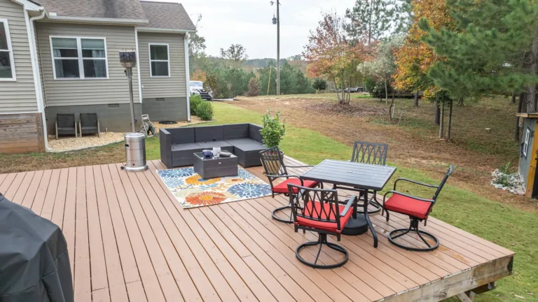 A wooden deck with a table and chairs on it in front of a house.