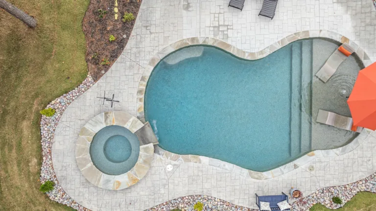 An aerial view of a large swimming pool surrounded by chairs and umbrellas.
