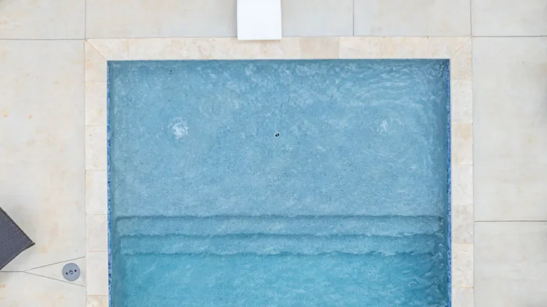 An aerial view of a swimming pool with blue water and steps.