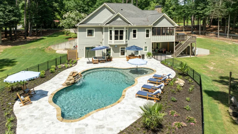 Backyard with kidney-shaped pool, patio loungers, and a two-story house surrounded by trees