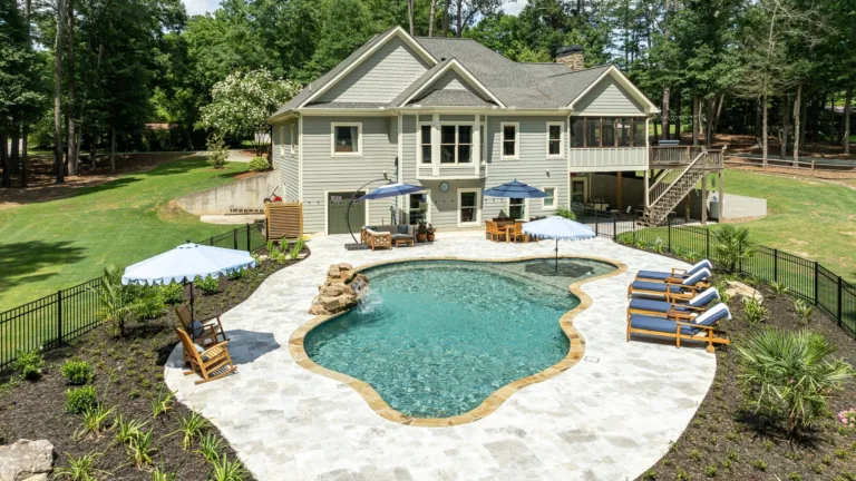 Backyard with kidney-shaped pool, patio chairs, umbrellas, and a two-story house surrounded by trees