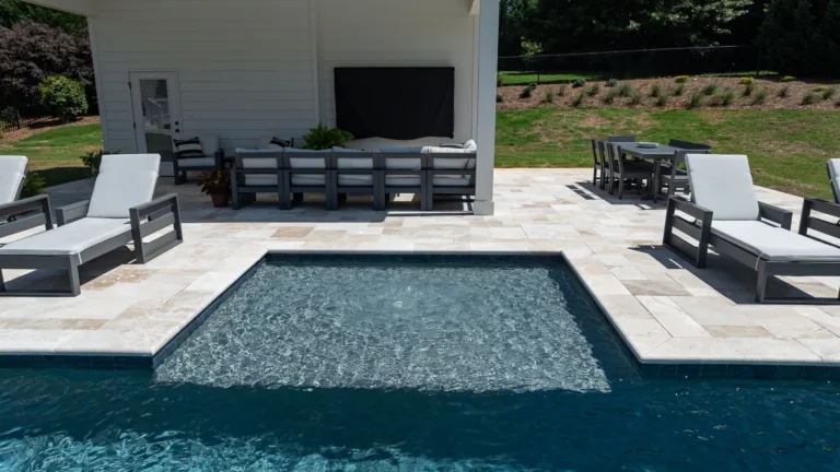 Backyard pool with a raised spa, lounge chairs, and a covered patio seating area